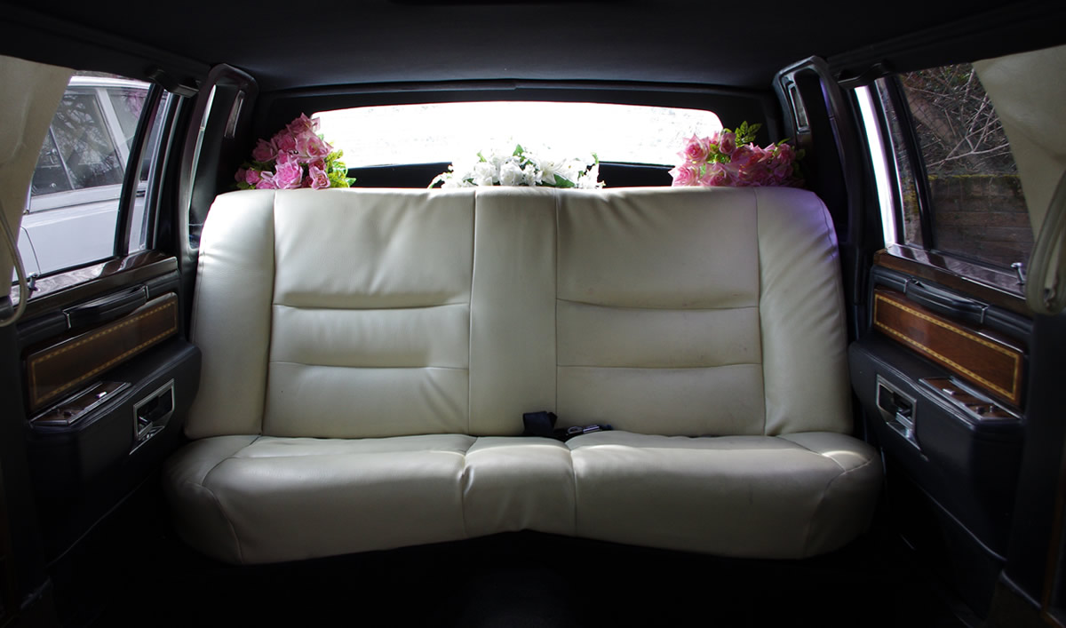 Interior view of an Excalibur limousine with white seating and flowers on display